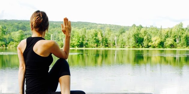 Entspannung: Frau sitzt am See und macht Yoga